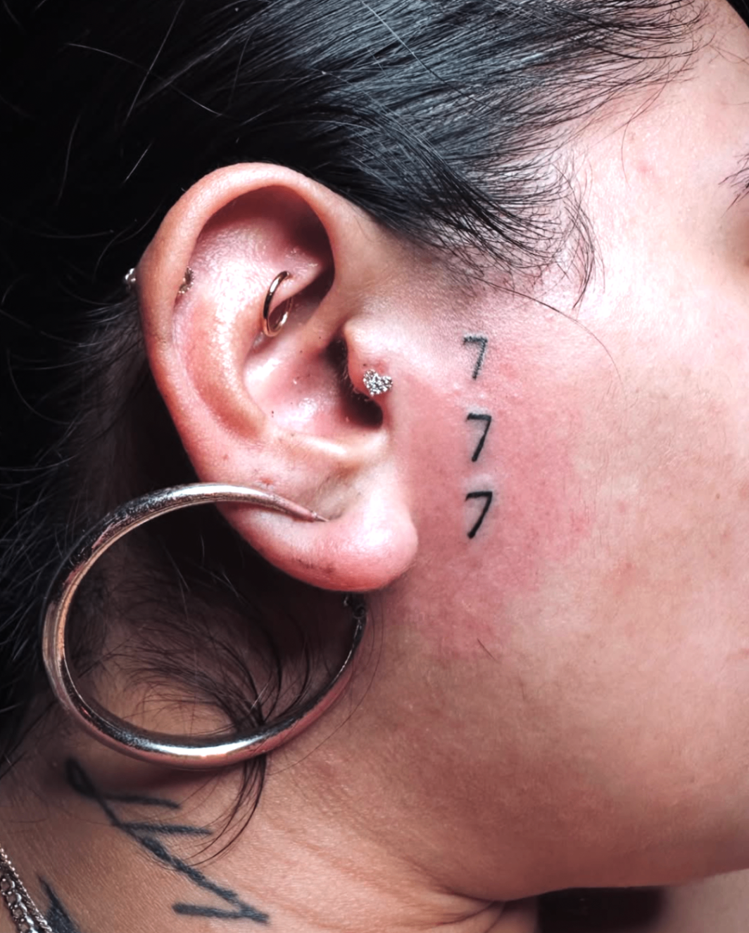 Minimal 777 angel number tattoo behind the ear