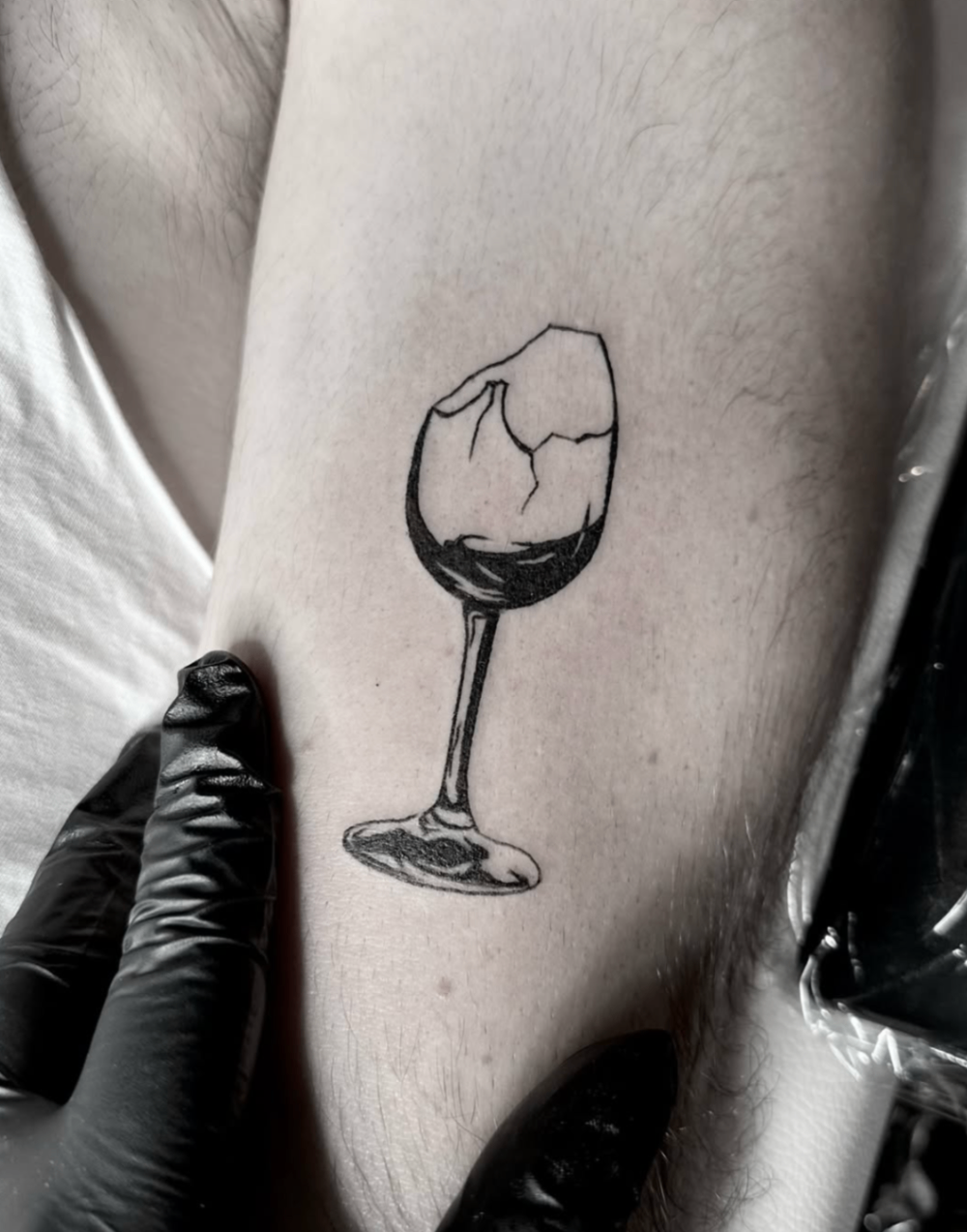 Cracked wine glass linework tattoo on inner arm